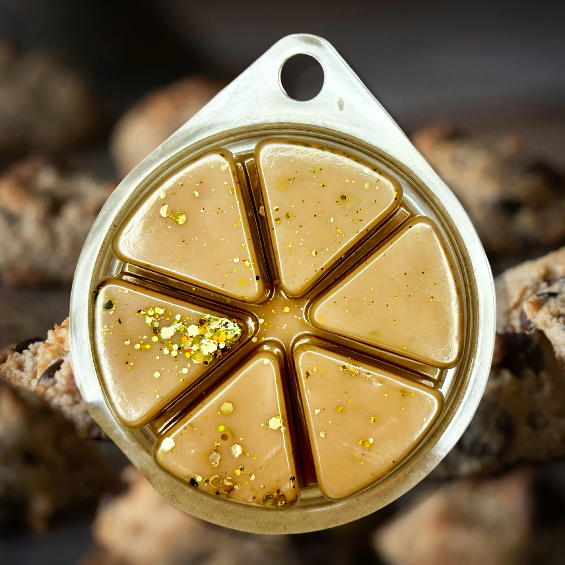 A close-up of a segmented, circular container holding the Who Stole The Cookie From The Cookie Jar Wax Melts 85g by The Soap Gal x reveals honeycomb-patterned golden liquid with glitter that gives off scented aromas reminiscent of freshly baked cookies.