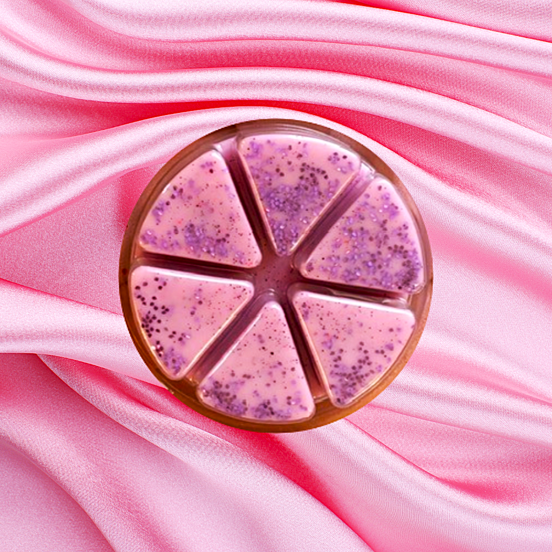 An 85g round container with five segments of pink and purple speckled Alien Luxury Wax Melts by The Soap Gals is elegantly placed on a pink satin fabric, exuding an enchanting fragrance that transports you to another realm.